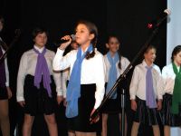 grupa śpiewających dziewcząt - białe bluzki, kolorowe szaliki